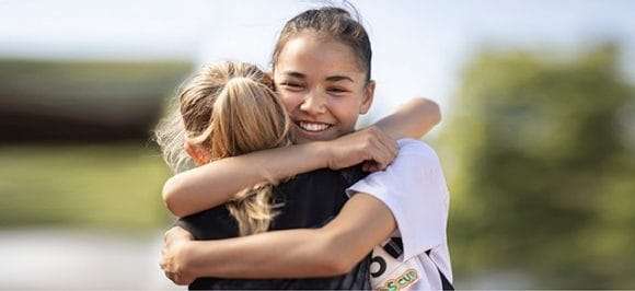 Two sportswomen embrace each other